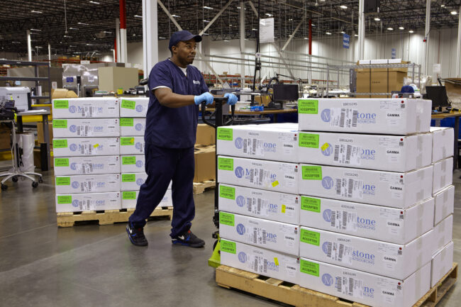 image of a person in logistics about to pull a pallet of stacked packages