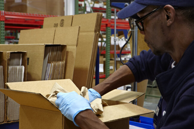 image of a man in logistics warehouse packaging a box
